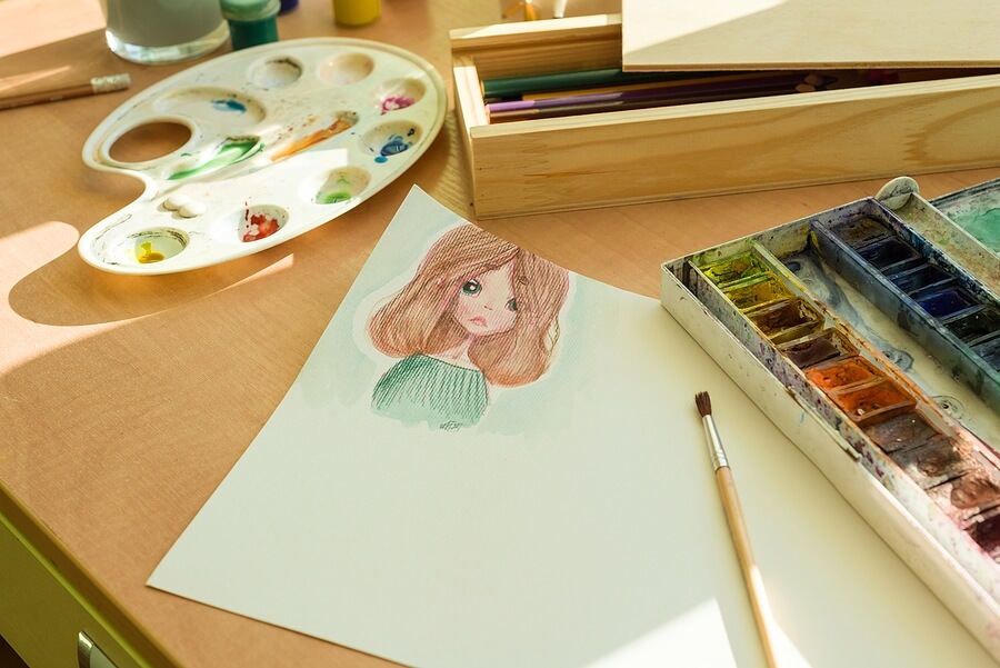Drawing by watercolor - anime girl, on a table with watercolor paint brush.