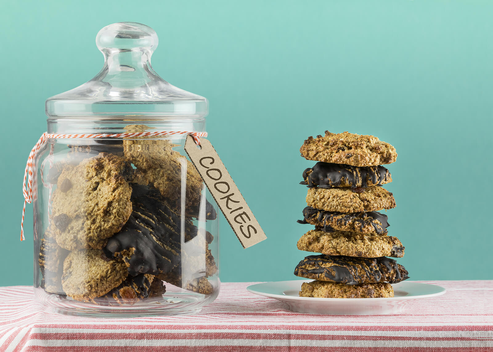 front view of a stack of chocolate and raisin oatmeal cookies and a cookie jar