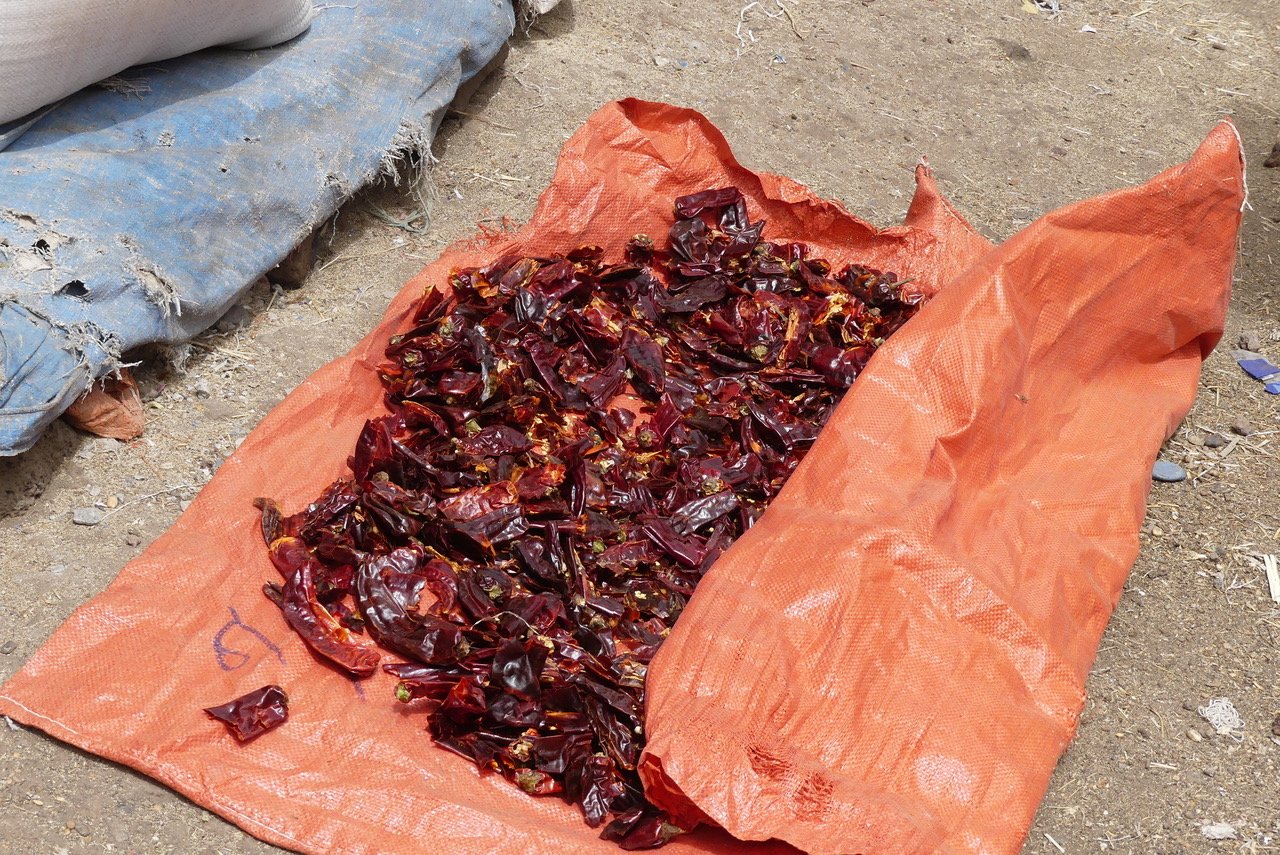 Chillies drying on the ground in a market.